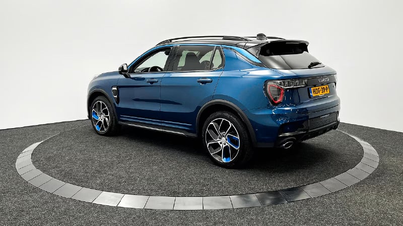 Blauwe SUV met zwarte en blauwe lichtmetalen velgen, geparkeerd op een RODISK met grijze vloerbedekking. De auto is schuin gepositioneerd, waarbij de achterkant en rechterzijde zichtbaar zijn. Nederlandse kentekenplaat HDF-39-P