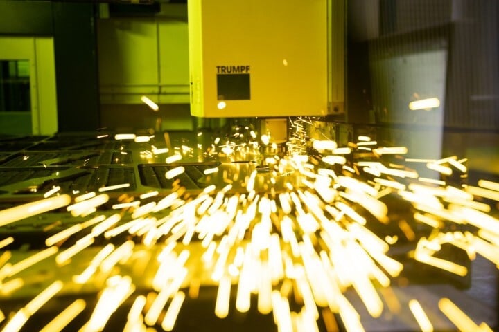 close-up van TRUMPF lasersnijmachine die metaal snijdt met felgele vonken in industriële omgeving