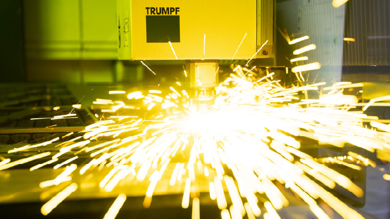 TRUMPF lasersnijmachine in werking, met heldere gele vonken tijdens het snijden van metaal.