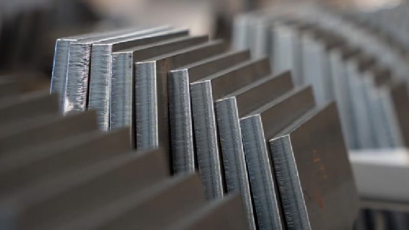 Close-up van meerdere metalen platen in een verspringende, overlappende opstelling met gladde, reflecterende oppervlakken en zichtbare randen.