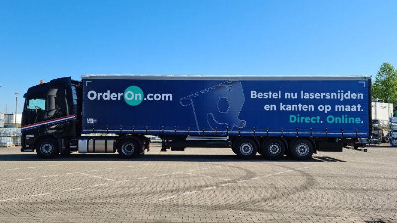 Grote vrachtwagen met trailer geparkeerd op een verharde ondergrond onder een blauwe lucht, met reclame voor OrderOn.com: 
