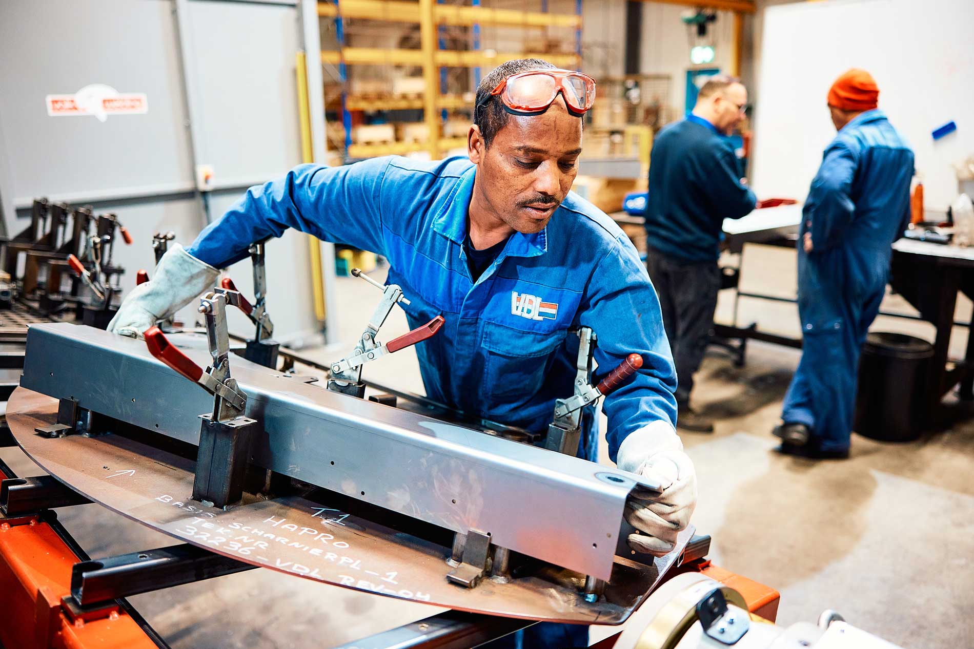 medewerker vdl blauwe jas bezig met een koker metaal